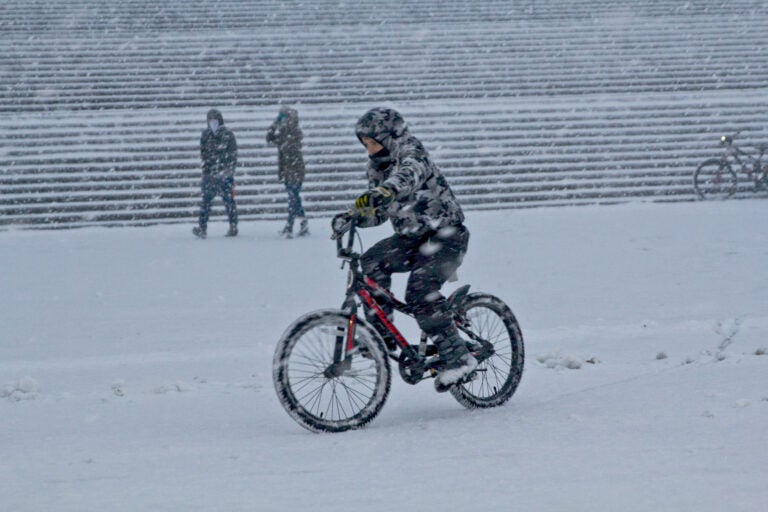 A person rides a bike during a snow storm outside the Philly Art Museum