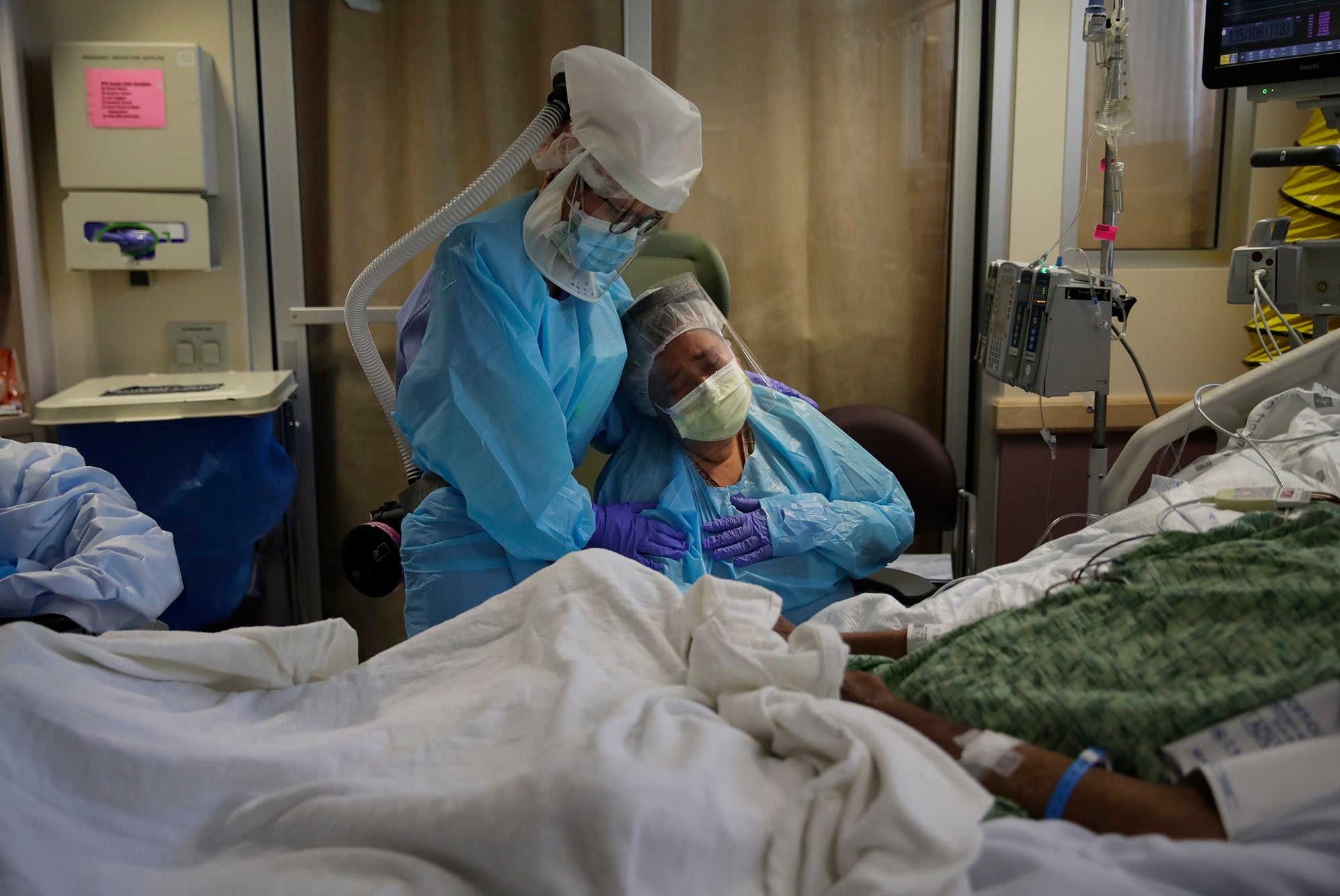 Romelia Navarro, right, is comforted by nurse Michele Younkin, left, as she weeps while sitting at the bedside of her dying husband