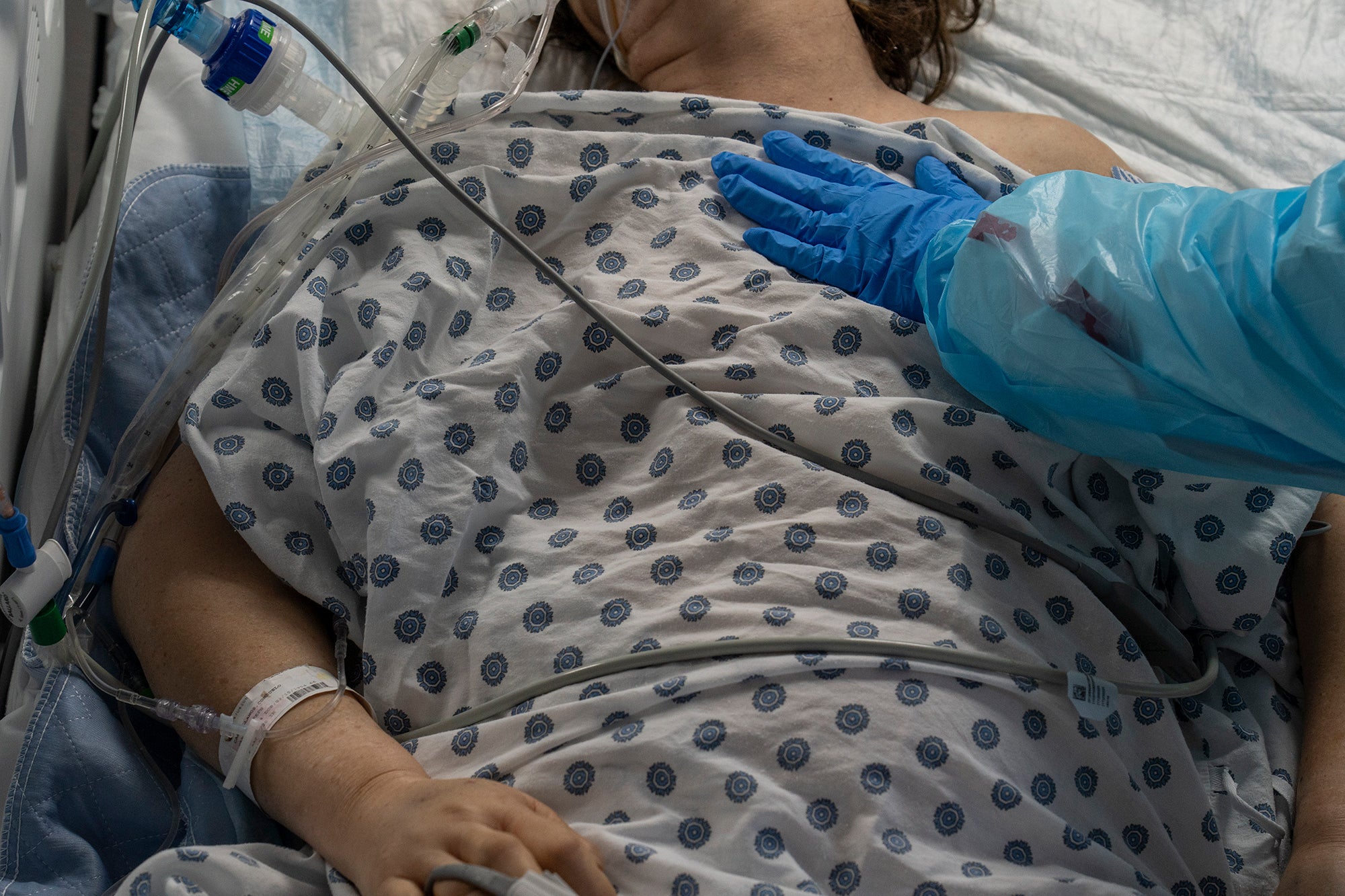 Medical staff member Susan Paradela places her hand on a patient