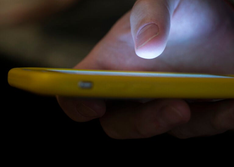 In this Sunday, Aug. 11, 2019, photo, a man uses a cell phone in New Orleans. With suicides on the rise, the government wants to make the national crisis hotline easier to reach. Once implemented, people will just need to dial 988 to seek help. Currently, National Suicide Prevention Lifeline uses a 10-digit number, 800-273-TALK (8255). Callers are routed to one of 163 crisis centers, where counselors answered 2.2 million calls last year