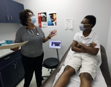 Jeremiah Young, 11, right, listens as Dr. Janice Bacon, a primary care physician, with Central Mississippi Health Services explains the necessity of receiving inoculations prior to attending school, Aug. 14, 2020, while at the Community Health Care Center on the Tougaloo College campus in Tougaloo, Miss. (Rogelio V. Solis/AP Photo)
