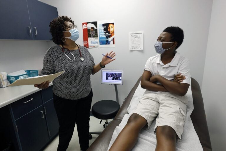 Jeremiah Young, 11, right, listens as Dr. Janice Bacon, a primary care physician, with Central Mississippi Health Services explains the necessity of receiving inoculations prior to attending school, Aug. 14, 2020, while at the Community Health Care Center on the Tougaloo College campus in Tougaloo, Miss. (Rogelio V. Solis/AP Photo)