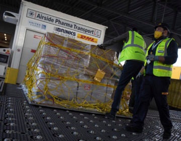 Cargo workers move a palette of cool boxes and other items into a pharma transport container during a demonstration on the handling and logistics of vaccines and medicines at the DHL cargo warehouse in Steenokkerzeel, Belgium, Tuesday, Dec. 1, 2020. (AP Photo/Virginia Mayo)