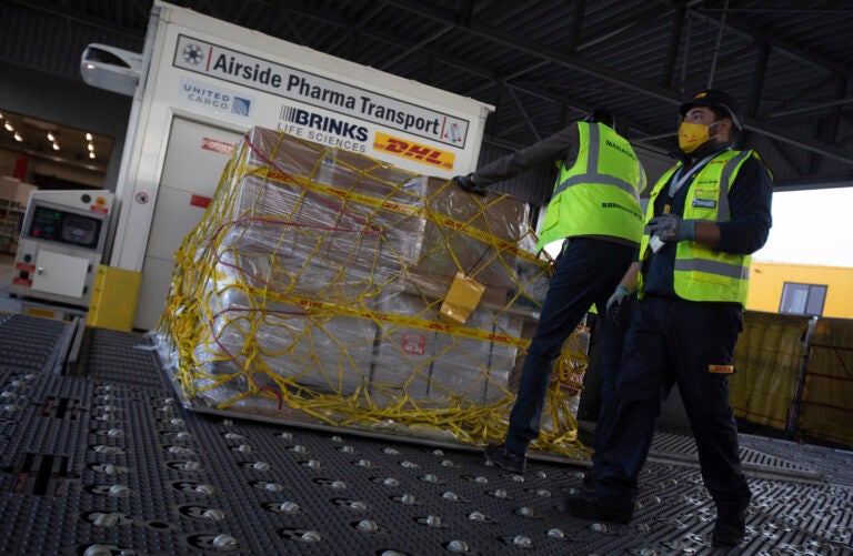 Cargo workers move a palette of cool boxes and other items into a pharma transport container during a demonstration on the handling and logistics of vaccines and medicines at the DHL cargo warehouse in Steenokkerzeel, Belgium, Tuesday, Dec. 1, 2020. (AP Photo/Virginia Mayo)