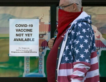 A pedestrian wearing a mask walks past a sign advising that COVID-19 vaccines are not available yet at a Walgreen’s pharmacy store during the coronavirus outbreak in San Francisco, Wednesday, Dec. 2, 2020. (AP Photo/Jeff Chiu)