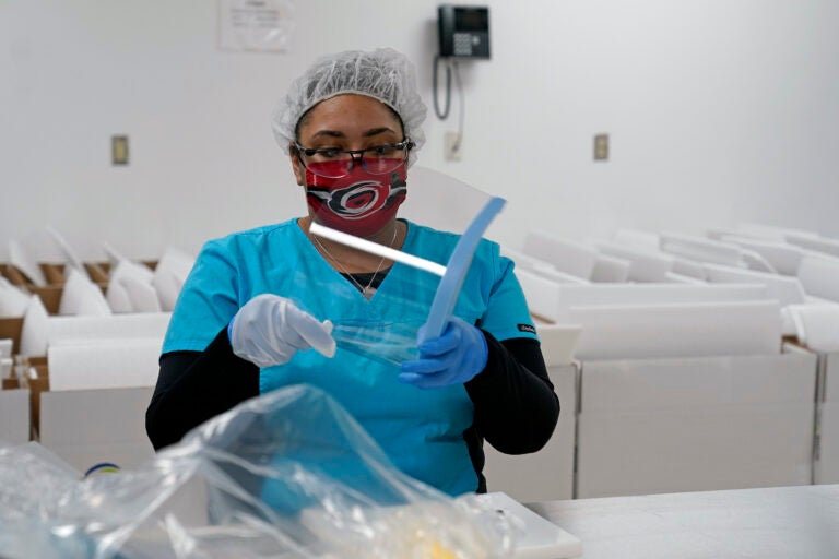 Gilero employee Anne-Marie Dutch assembles a face shield in Pittsboro, N.C., as Gov. Roy Cooper tours the facility Thursday, Dec. 3, 2020. The medical device manufacturer began producing face shields when the pandemic started and also produces swabs for rapid tests in addition to self contained oxygenated negative pressure environments. (AP Photo/Gerry Broome)