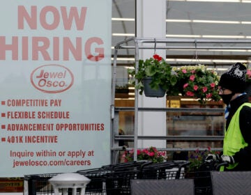 A man pushes carts as a hiring sign shows at a Jewel Osco grocery store in Deerfield, Ill., Thursday, April 23, 2020. (AP Photo/Nam Y. Huh)