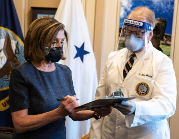 Speaker of the House Nancy Pelosi, D-Calif., signs a form next to Dr. Brian Monahan, attending physician Congress of the United States after she received a Pfizer-BioNTech COVID-19 vaccine shot in Washington, Friday, Dec. 18, 2020. (Anna Moneymaker/The New York Times via AP, Pool)