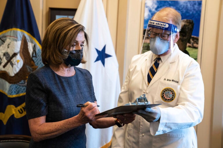 Speaker of the House Nancy Pelosi, D-Calif., signs a form next to Dr. Brian Monahan, attending physician Congress of the United States after she received a Pfizer-BioNTech COVID-19 vaccine shot in Washington, Friday, Dec. 18, 2020. (Anna Moneymaker/The New York Times via AP, Pool)