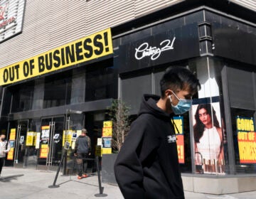 In this Wednesday, Sept. 30, 2020, file photo, a man wearing a mask amid the coronavirus pandemic walks by a Century 21 department store, in the Brooklyn borough of New York. (AP Photo/Mark Lennihan)