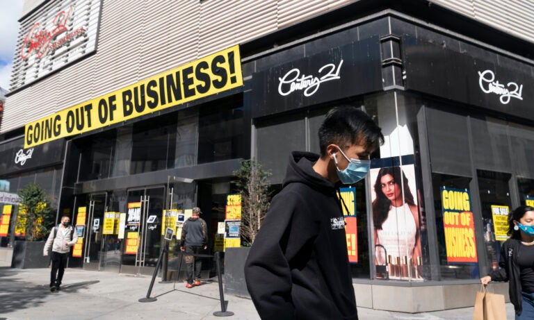 In this Wednesday, Sept. 30, 2020, file photo, a man wearing a mask amid the coronavirus pandemic walks by a Century 21 department store, in the Brooklyn borough of New York. (AP Photo/Mark Lennihan)