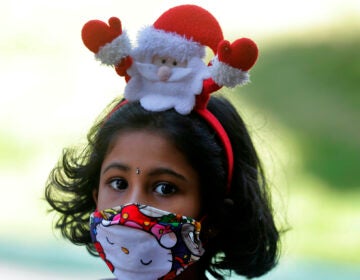 A Sri Lankan Catholic girl wears a hair band with a Santa figure arrives at a church to attend the Christmas Day holly mass in Colombo, Sri Lanka, Friday, Dec. 25, 2020. (AP Photo/Eranga Jayawardena)