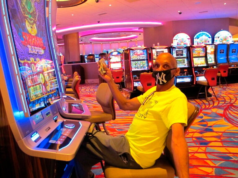 Gary Royster of Atlantic City holds up cash he used to gamble at the Hard Rock casino in Atlantic City on July 2, 2020, the day the casino reopened after being shut down for months amid the coronavirus outbreak. (AP Photo/Wayne Parry)