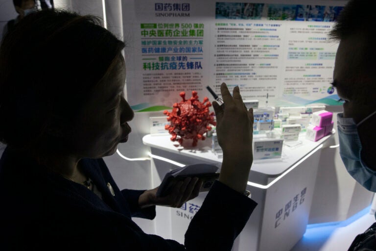 A promoter talks about the COVID-19 vaccine produced by Sinopharm subsidiary CNBG during a trade fair in Beijing on Sunday, Sept. 6, 2020. (AP Photo/Ng Han Guan)