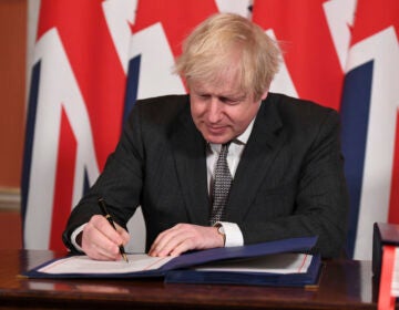 Britain's Prime Minister Boris Johnson signs the EU-UK Trade and Cooperation Agreement at 10 Downing Street, London Wednesday Dec. 30, 2020. (Leon Neal/Pool via AP)