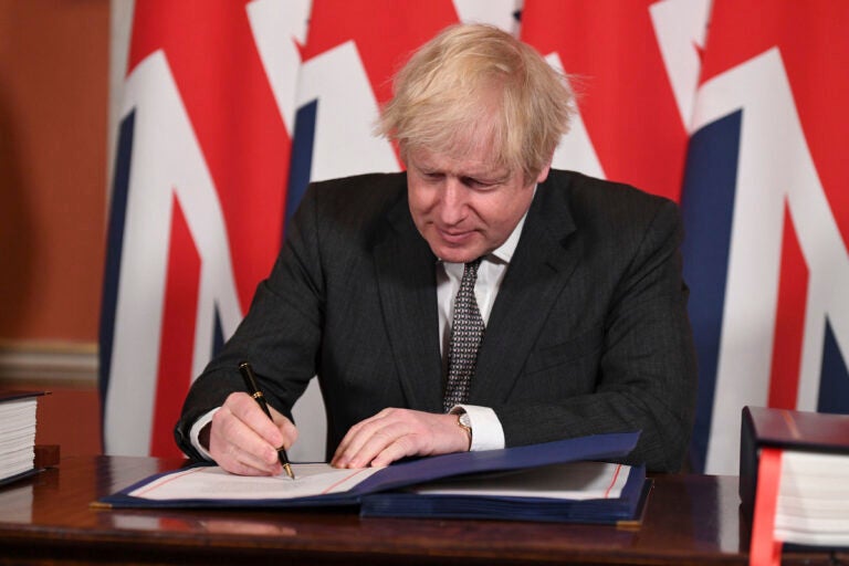 Britain's Prime Minister Boris Johnson signs the EU-UK Trade and Cooperation Agreement at 10 Downing Street, London Wednesday Dec. 30, 2020. (Leon Neal/Pool via AP)