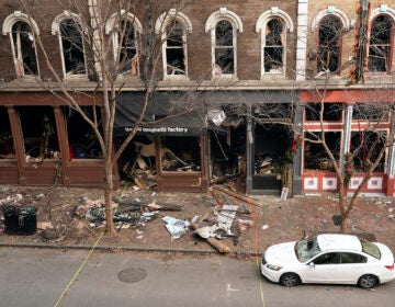 In this Dec. 29, 2020 file photo, debris remains on the sidewalk in front of buildings damaged in a Christmas Day explosion  in Nashville, Tenn. (AP Photo/Mark Humphrey)