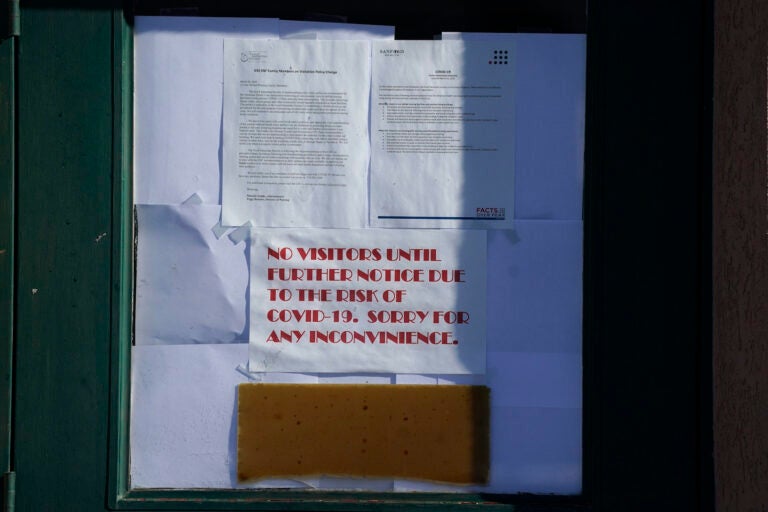 Signs hang on the door to the Good Samaritan Society care center, which is closed to the public Wednesday, Dec. 30, 2020, in Simla, Colo. (AP Photo/David Zalubowski)