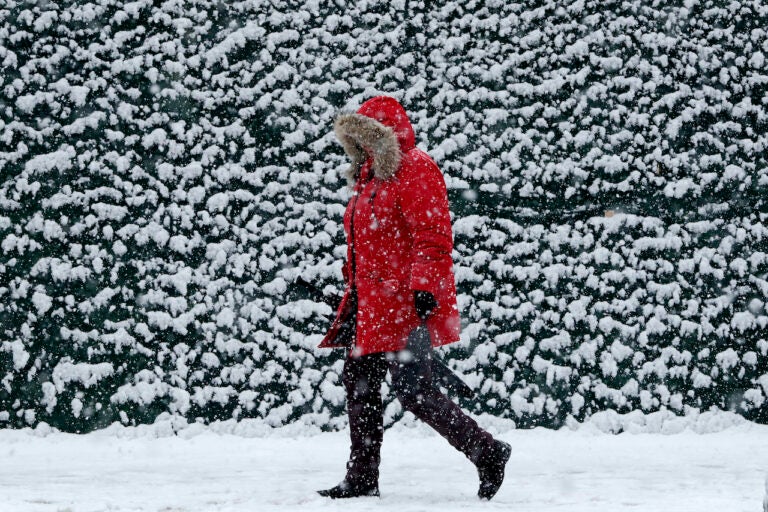 A woman approaches the Hoboken Terminal of the PATH train system as light snow falls at the beginning of a snowstorm