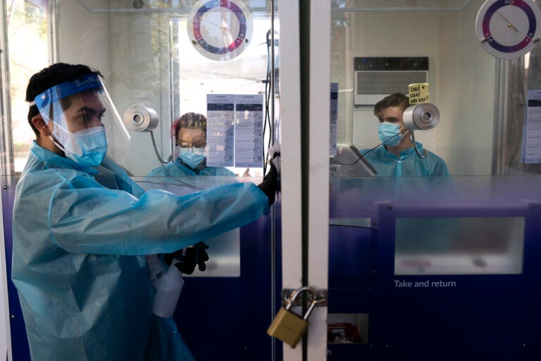 In this Dec. 9, 2020, file photo, test specialist Elijah Sanchez disinfects a testing booth at a COVID-19 testing site in Los Angeles.