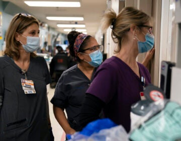 Registered nurse Kristina Shannon, from left, chaplain Andrea Cammarota, and ER charge nurse Cathy Carter watch as medical workers try to resuscitate a patient who tested positive for coronavirus in the emergency room