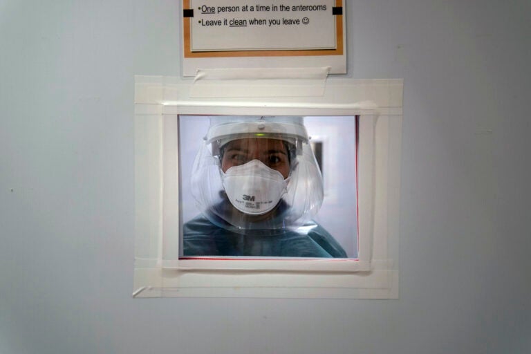 Registered nurse Nicole Grecco looks through a small window while working in a COVID-19 unit at Mission Hospital
