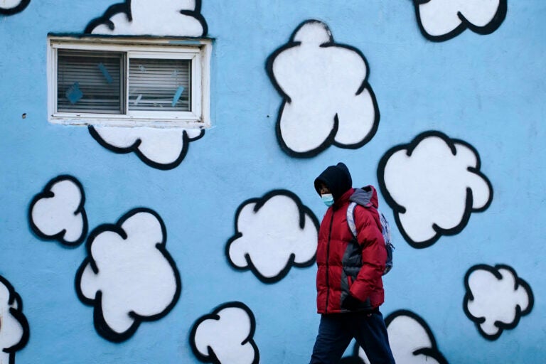 A person wearing a face mask to protect against the spread of the coronavirus walks along Market Street