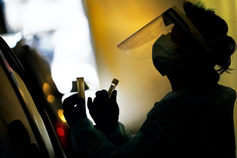 A health care worker wears personal protective equipment as she speaks with a patient at a mobile testing location