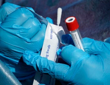 Registered nurse Tria Jones opens a swab during testing for COVID-19