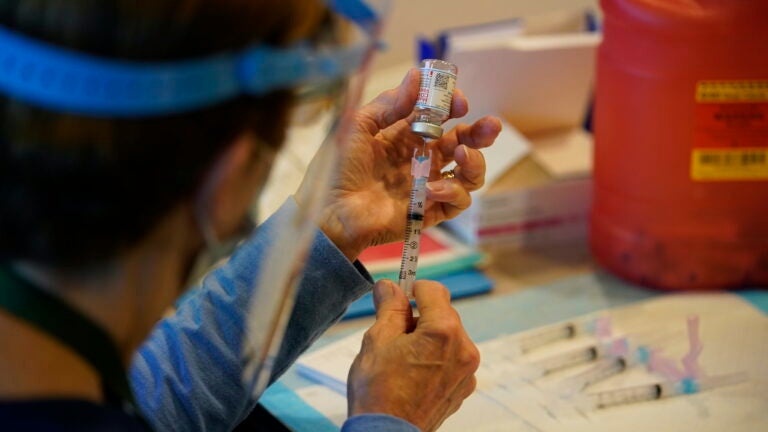 Pat Moore, with the Chester County, Pa., Health Department, fills a syringe with Moderna COVID-19 vaccine