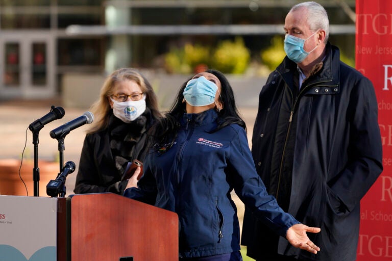 While New Jersey Gov. Phil Murphy, right, and New Jersey Health Commissioner Judith Persichilli, left, look on, Maritza Beniquez throws her head back and thanks God during a news conference at University Hospital's COVID-19 vaccine clinic at Rutgers New Jersey Medical School in Newark, N.J., Tuesday, Dec. 15, 2020.