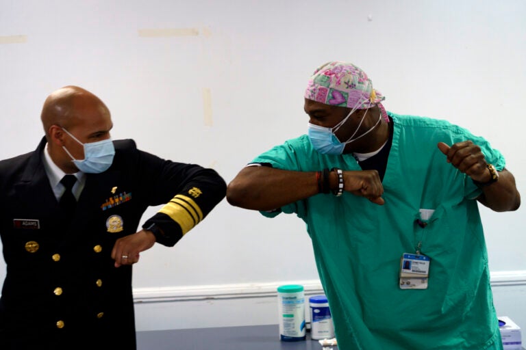 Surgeon General of the U.S. Jerome Adams, left, elbow-bumps Emergency Room technician Demetrius Mcalister after Mcalister got the Pfizer COVID-19 vaccination