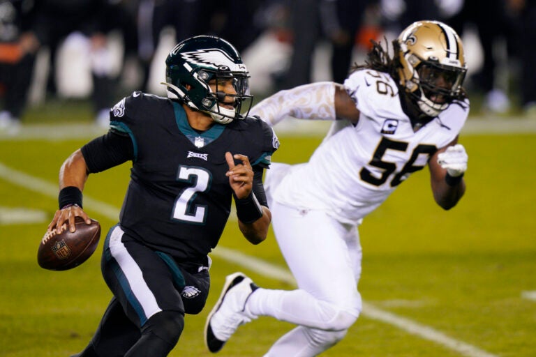 Philadelphia Eagles' Jalen Hurts, left, scrambles past New Orleans Saints' Demario Davis