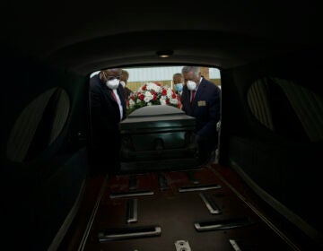 Mortician Cordarial O. Holloway, foreground left, funeral director Robert L. Albritten, foreground right, and funeral attendants Eddie Keith, background left, and Ronald Costello place a casket into a hearse