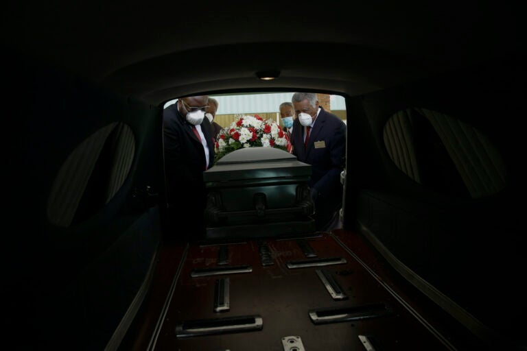 Mortician Cordarial O. Holloway, foreground left, funeral director Robert L. Albritten, foreground right, and funeral attendants Eddie Keith, background left, and Ronald Costello place a casket into a hearse