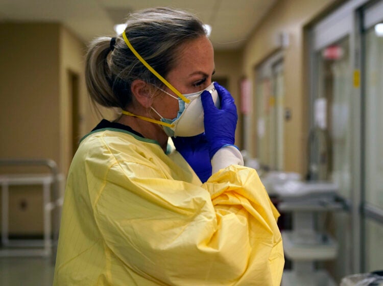 Registered nurse Chrissie Burkhiser puts on personal protective equipment as she prepares to treat a COVID-19 patient in the in the emergency room