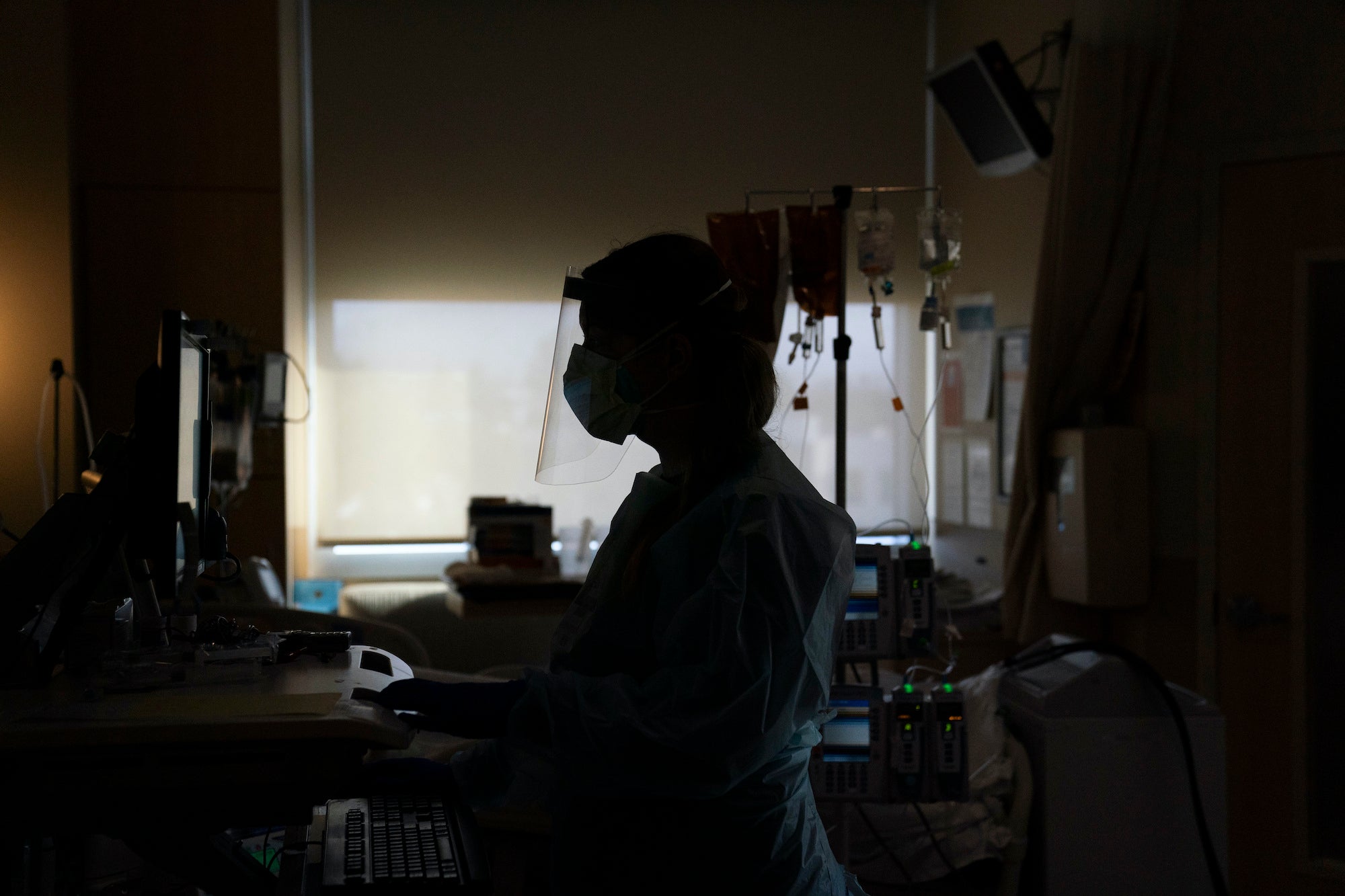 Registered nurse Virginia Petersen works on a computer while assisting a COVID-19 patient