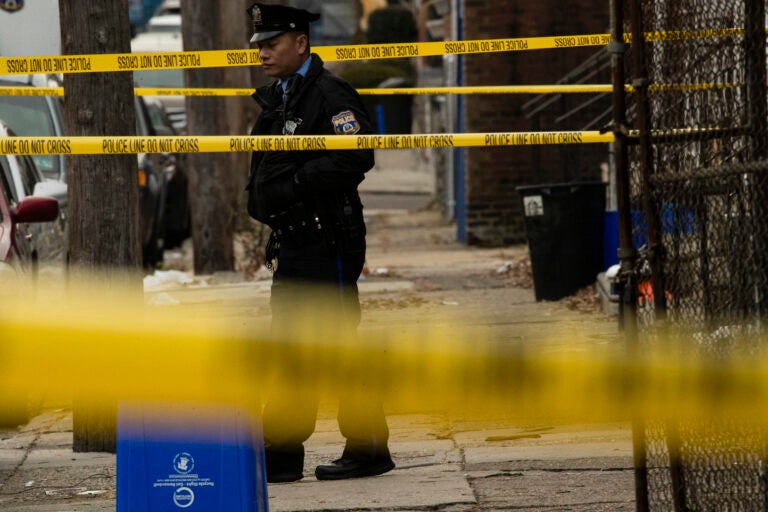 A Philadelphia police officer stands by a crime scene on Woodstock Street