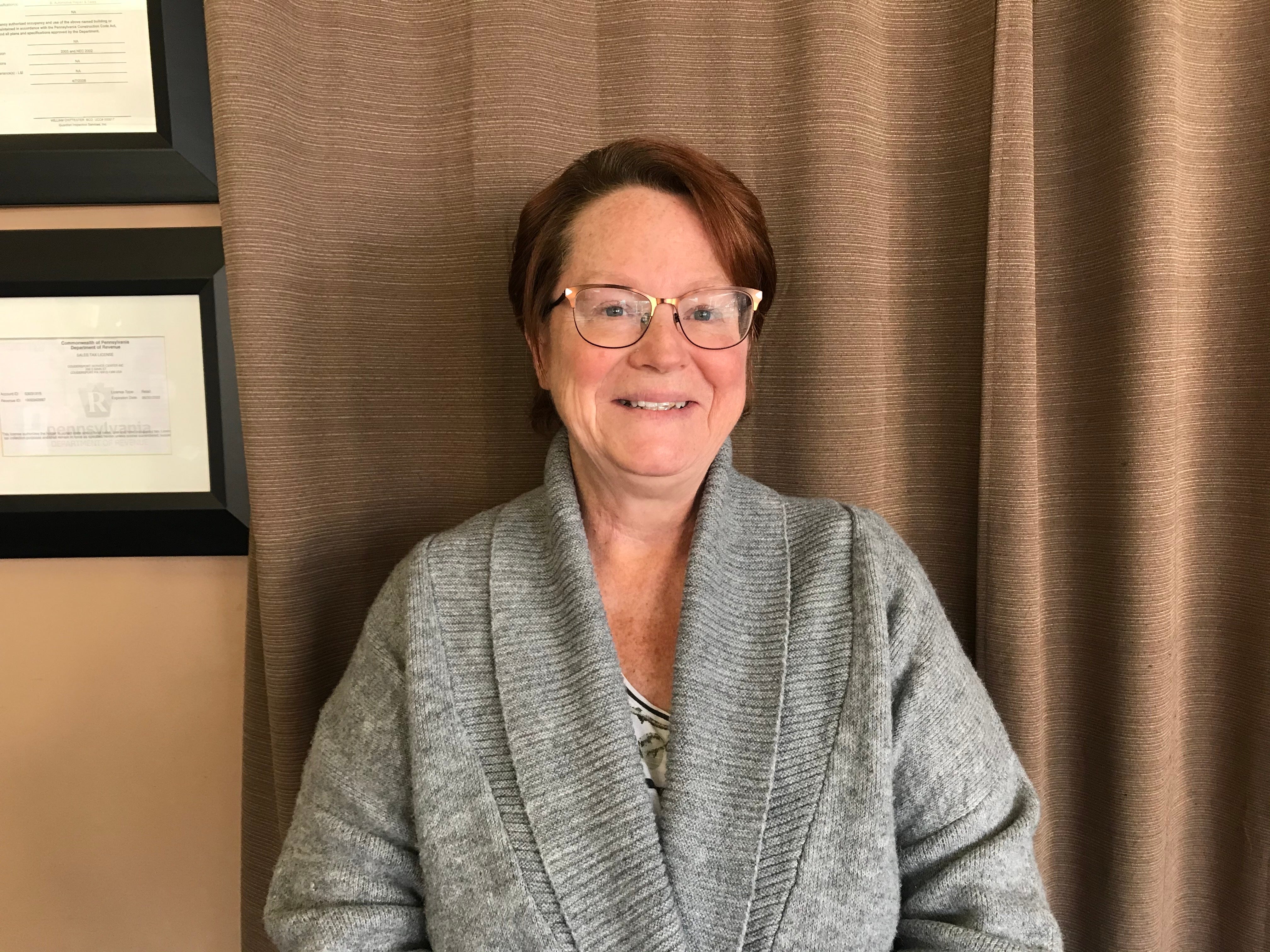 Brenda Baer stands in front of a curtain