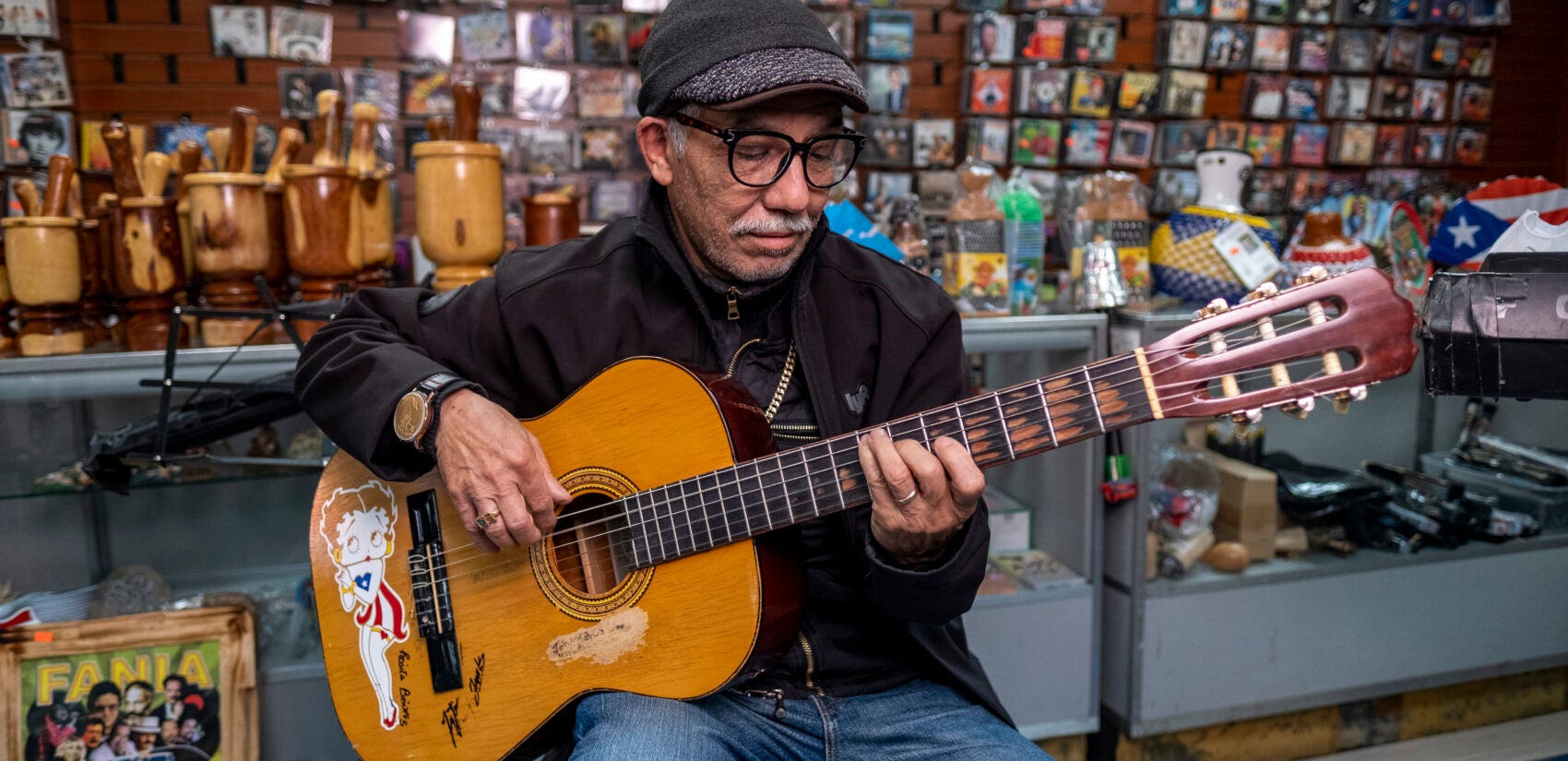 Friend and regular, Johnny Cruz playing the guitar at Centro Musical. His guitar features Betty Boop wearing the Puerto Rican flag. | Amigo y habitual, Johnny Cruz tocando la guitarra en Centro Músical. Su guitarra presenta a Betty Boop con la bandera de Puerto Rico.