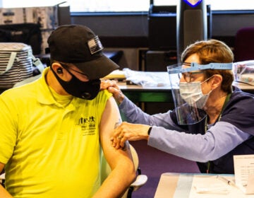 James Kerr, an EMT with Emergency Medical Staffing Solutions, is prepped to receive the Moderna COVID-19 vaccine from public health nurse Pat Moore