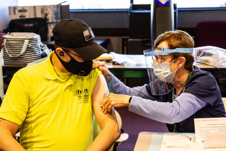 James Kerr, an EMT with Emergency Medical Staffing Solutions, is prepped to receive the Moderna COVID-19 vaccine from public health nurse Pat Moore