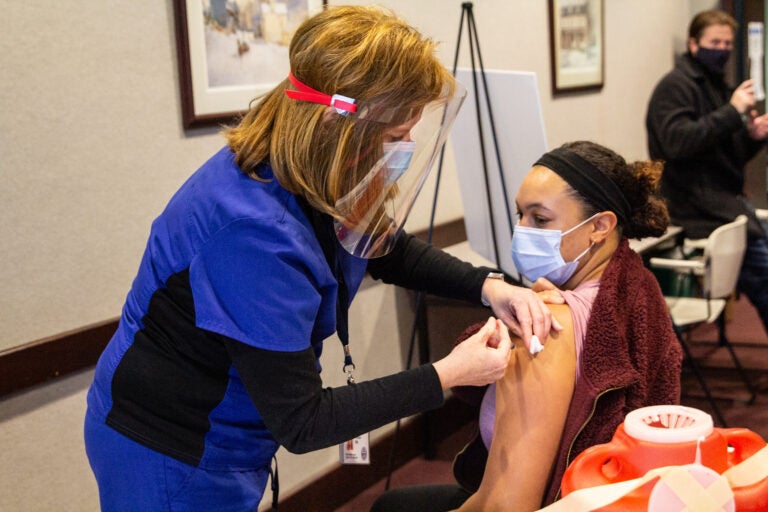 Allison Brown, Union Mills Chadds Ford School District nurse, receives the Moderna COVID-19 vaccine from RN Penny Caracas. (Kimberly Paynter/WHYY)