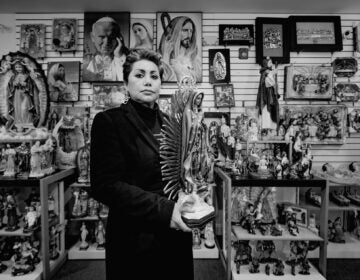 Isabel poses with a figure of the Virgen de Guadalupe (Virgin Mary). Mexican Catholics are fervently devoted to the Virgen de Guadalupe and celebrate her birthday every December 12th. | Isabel posa con una figura de la Virgen de Guadalupe (Virgen María). Los católicos mexicanos están fervientemente devotos de la Virgen de Guadalupe y celebran su cumpleaños cada 12 de diciembre. (Photo by Eugenio Salas for WHYY)