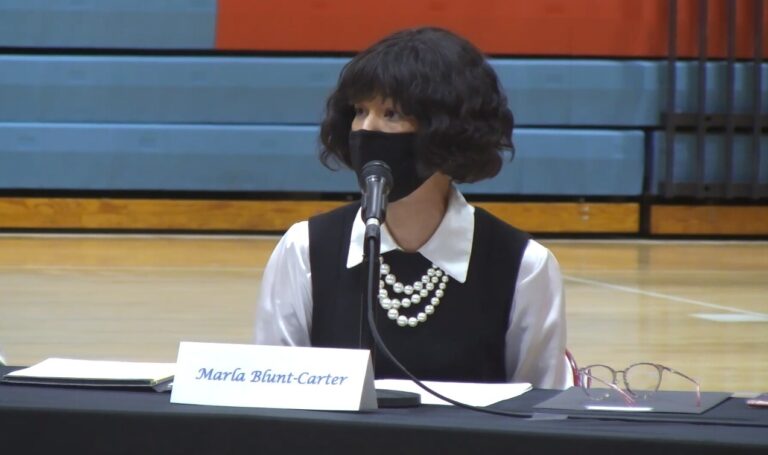 Elector Marla Blunt-Carter sits in front of a mic while wearing a mask