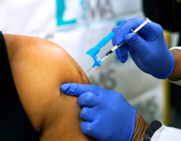 Dr. Timothy Quinn, owner of Quinn Health Care, left, receives the first round of the Pfizer COVID vaccination