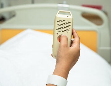 Woman holding and pushing hand emergency button in hospital