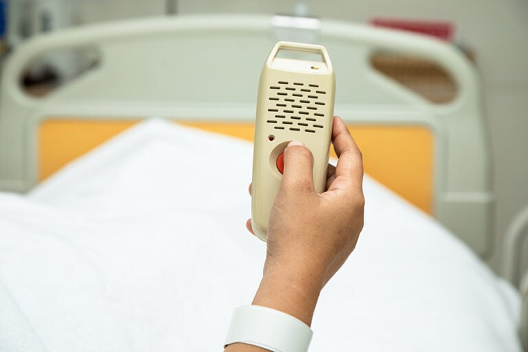 Woman holding and pushing hand emergency button in hospital