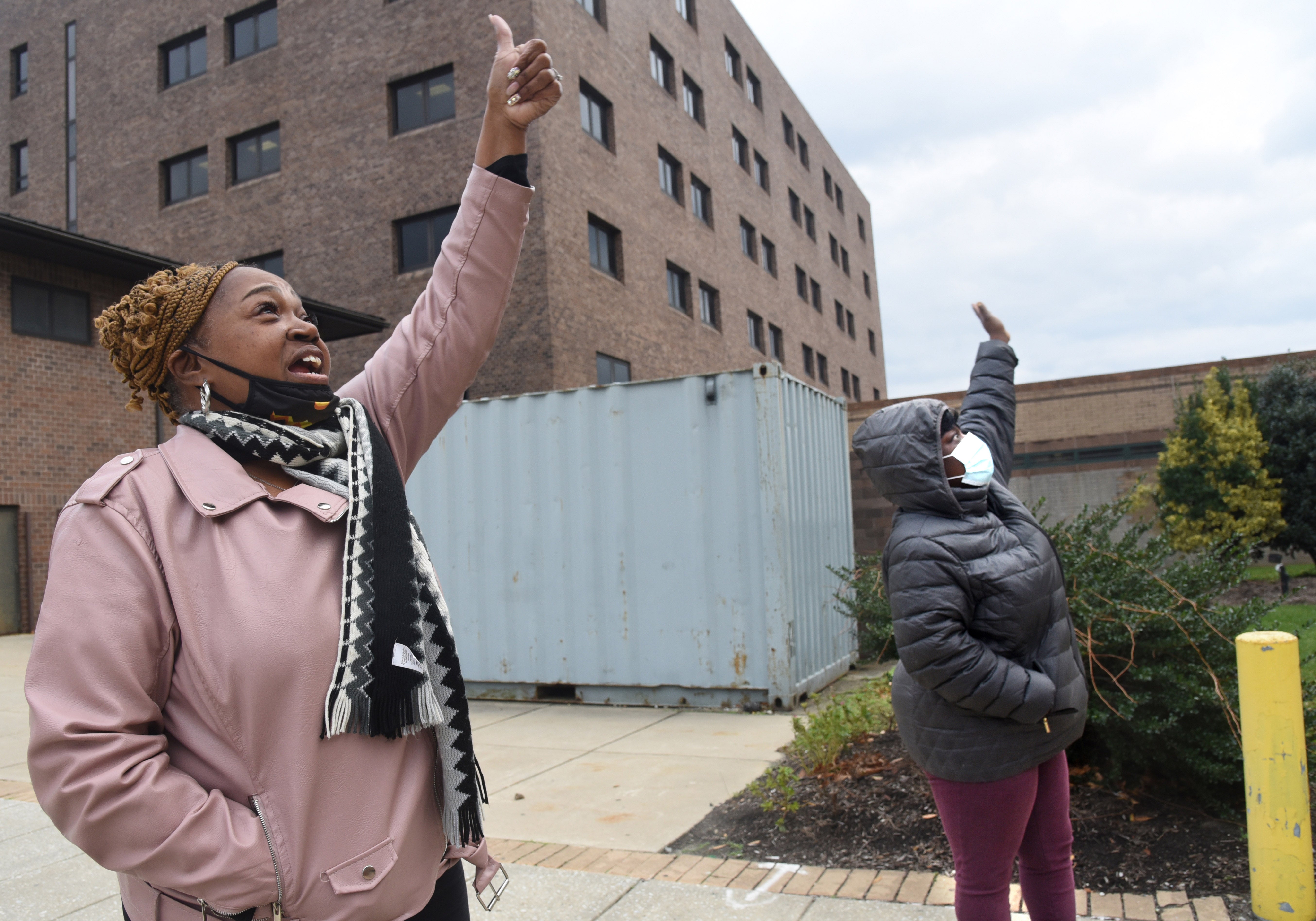 Connie Kellum and LaToya Fields give thumbs up to people who are incarcerated watching from windows from outside the Camden County jail.