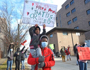 Leemaj Banks, 5, holds a sign while in the arms of his uncle Geovanni Andujar